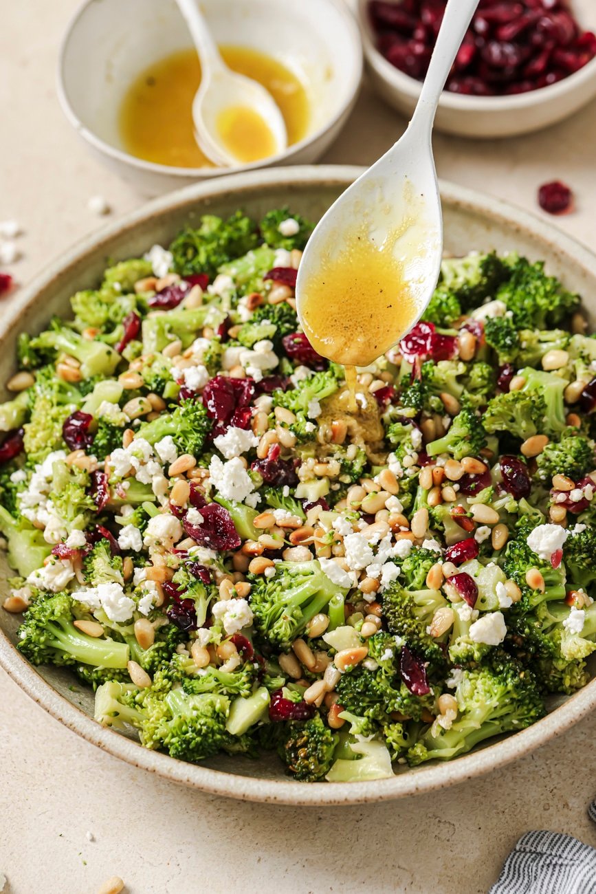 Drizzling dressing onto warm broccoli salad.