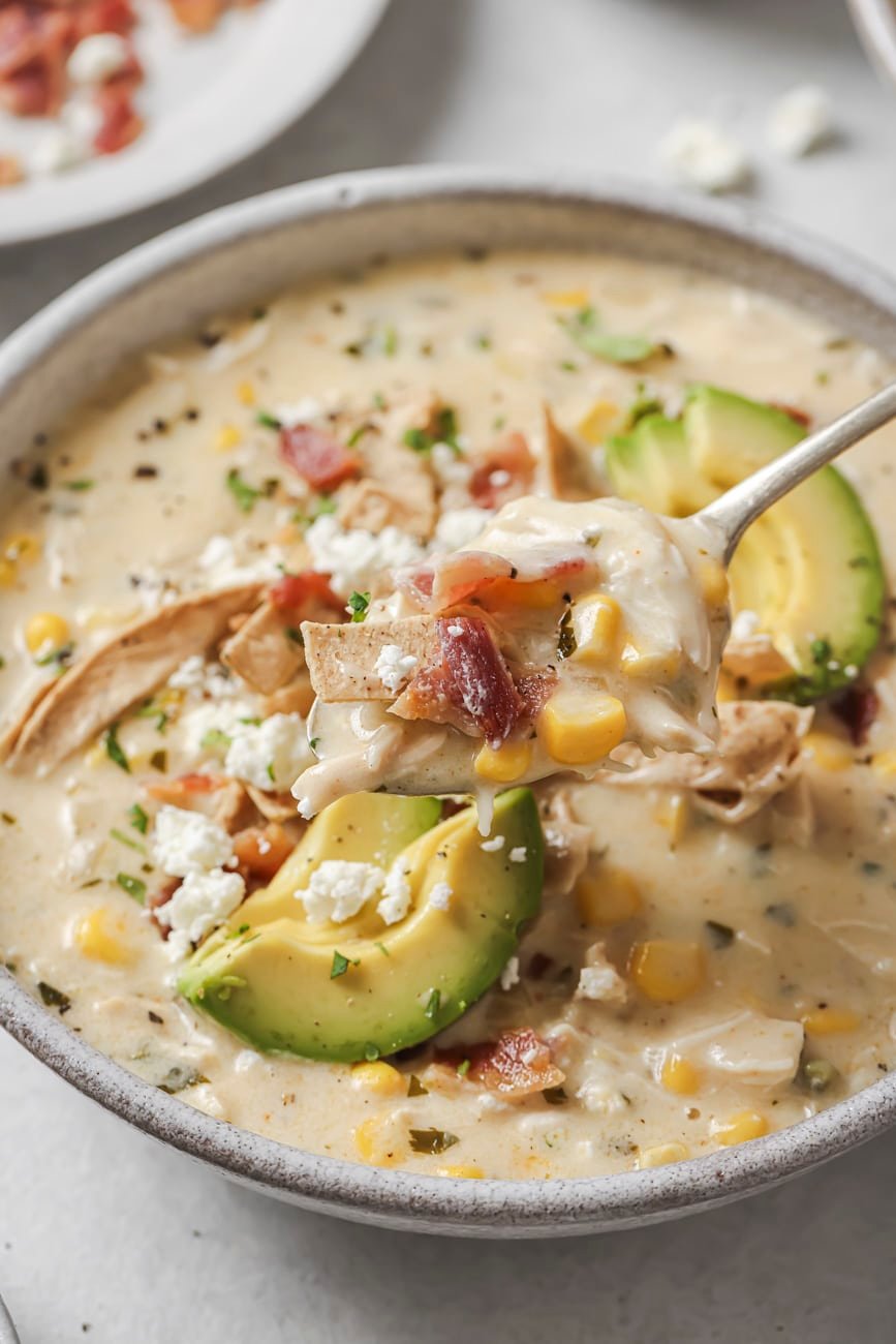 Taking a spoonful of white chicken chili from a bowl.