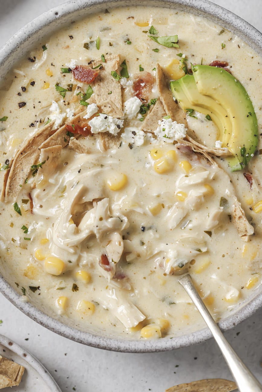 Overhead closeup of white chicken chili in a bowl with toppings.