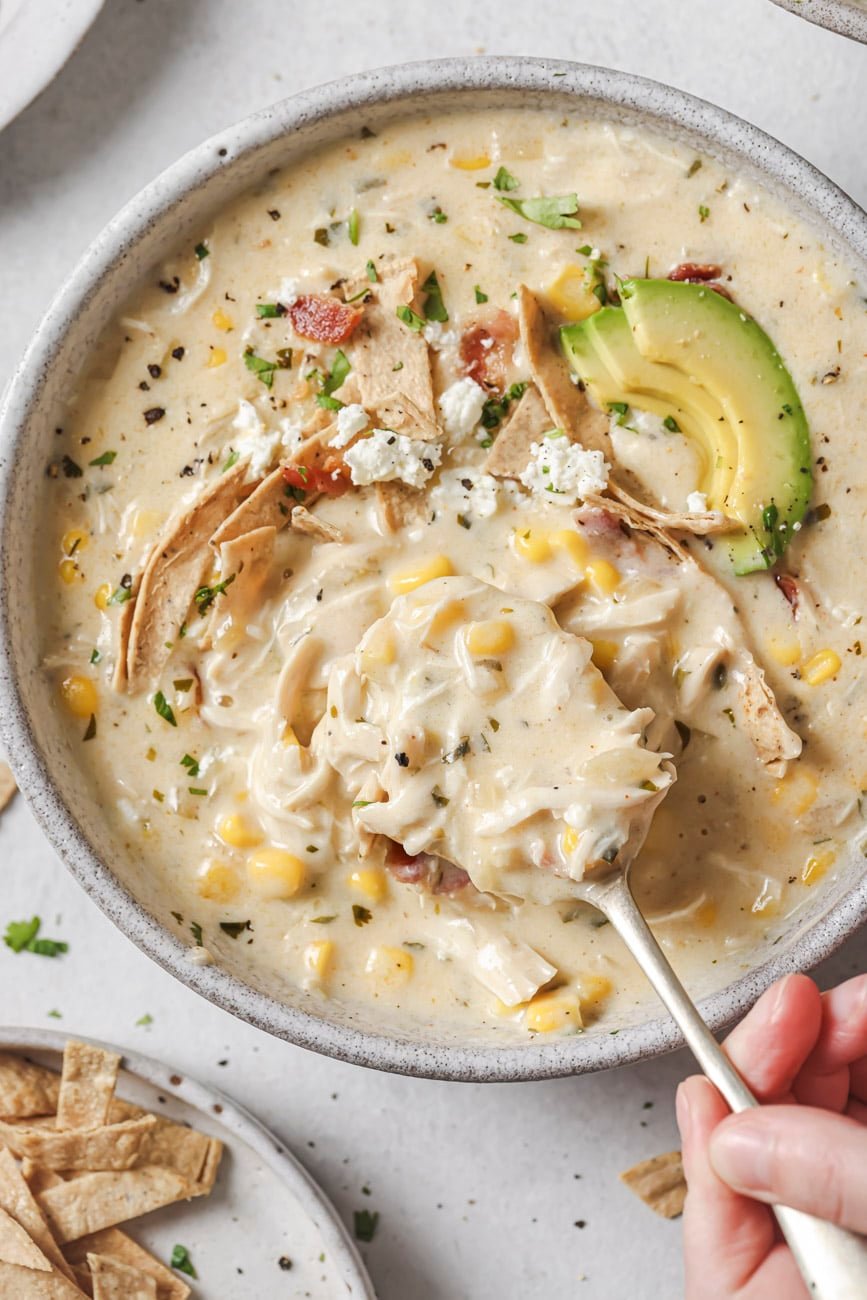 Taking a spoonful of white chicken chili from a bowl.