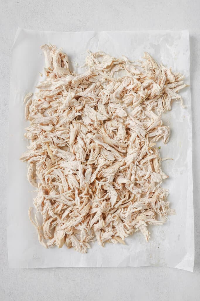 Cooked shredded chicken on a piece of parchment paper.