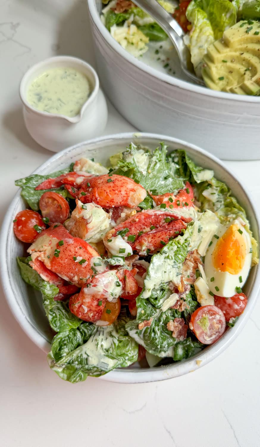 lobster salad in a small white bowl with tarragon dressing on the side.