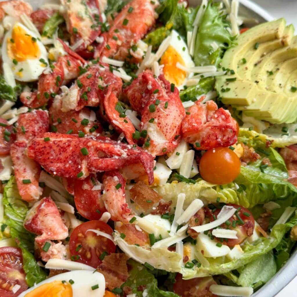 close up of a lobster salad with avocado, egg, and cheese.