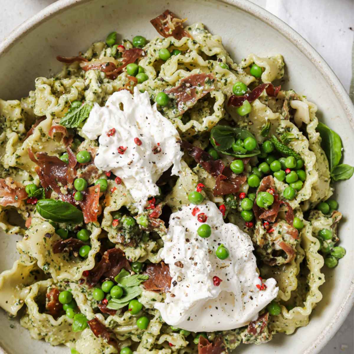 Closeup overhead shot of a bowl of pesto prosciutto pasta.