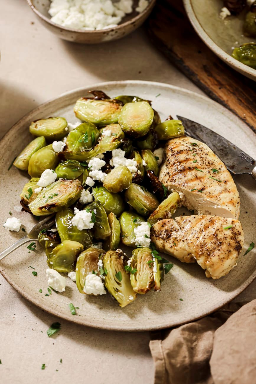 A plate of grilled chicken and air fryer brussels sprouts with maple syrup.