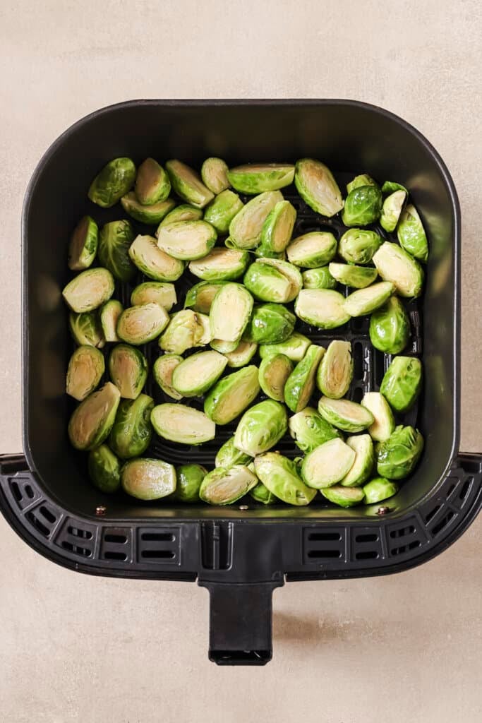 Halved brussels sprouts in the air fryer basket.