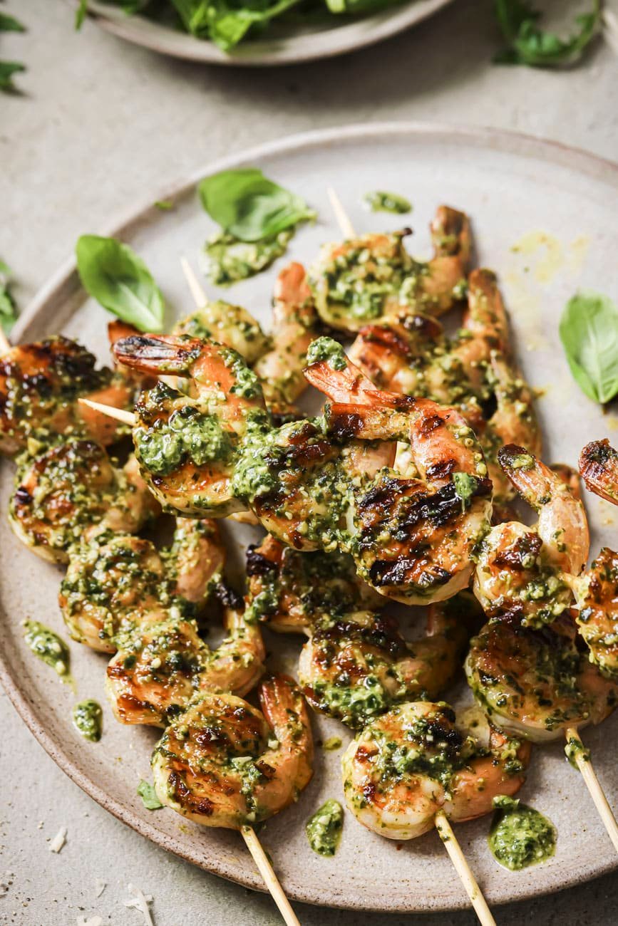 skewered grilled pesto shrimp on a white plate.