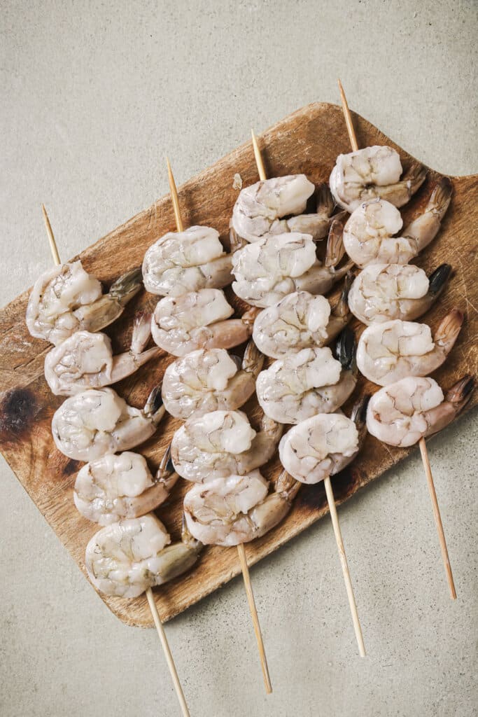 Raw shrimp on wooden skewers.