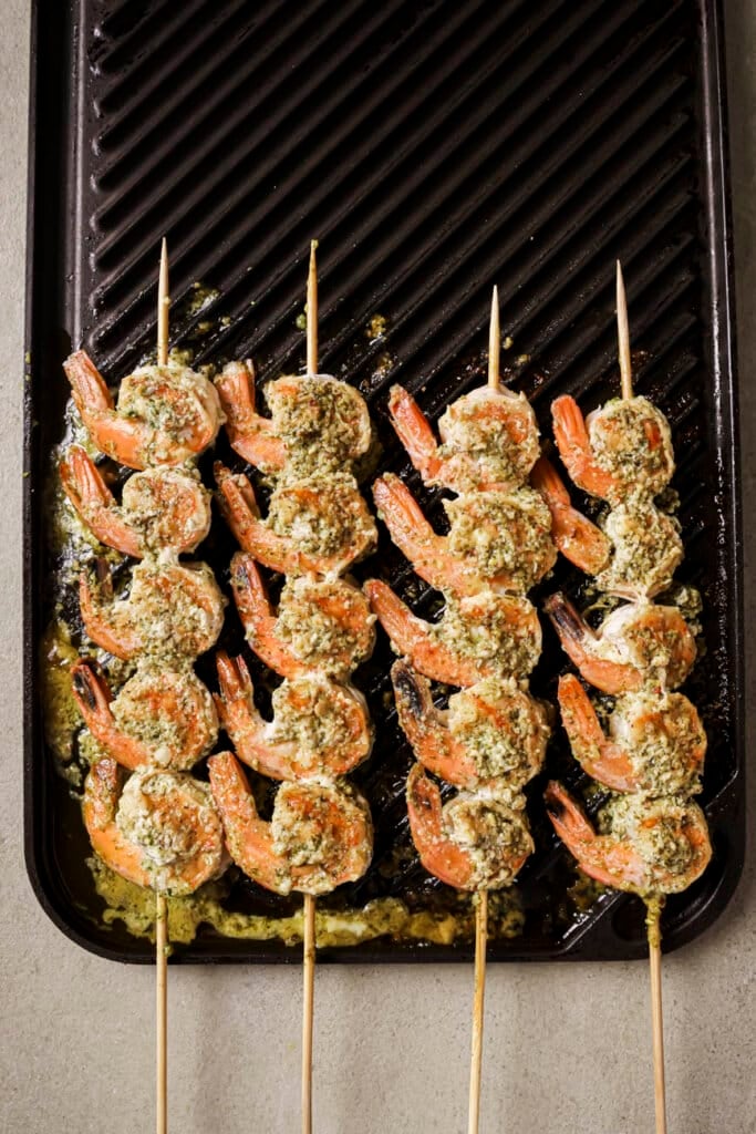 shrimp on wooden skewers cooking on a grill grate