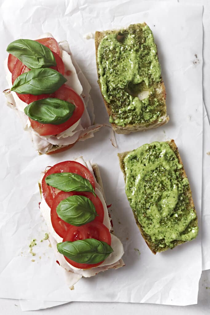 Adding mozzarella, tomato, and basil to sanwiches.