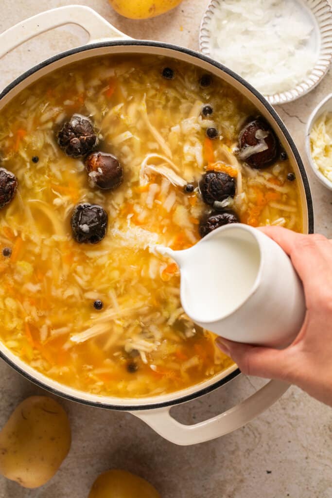 Pouring cream into pickle soup.