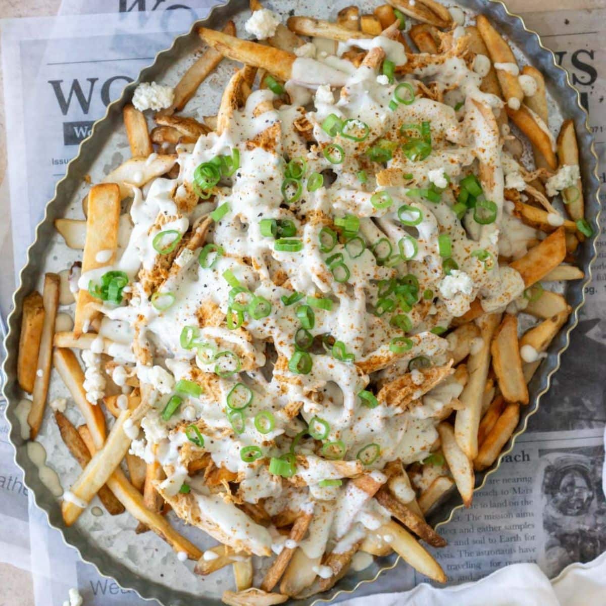 chicken poutine in a serving dish topped with green onions