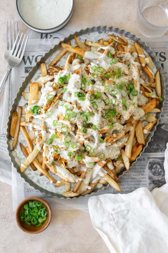 This Chicken Poutine Recipe is your new-found addiction. Crispy fries are smothered topped with Old Bay seasoned chicken and then smothered in a creamy blue cheese gravy.