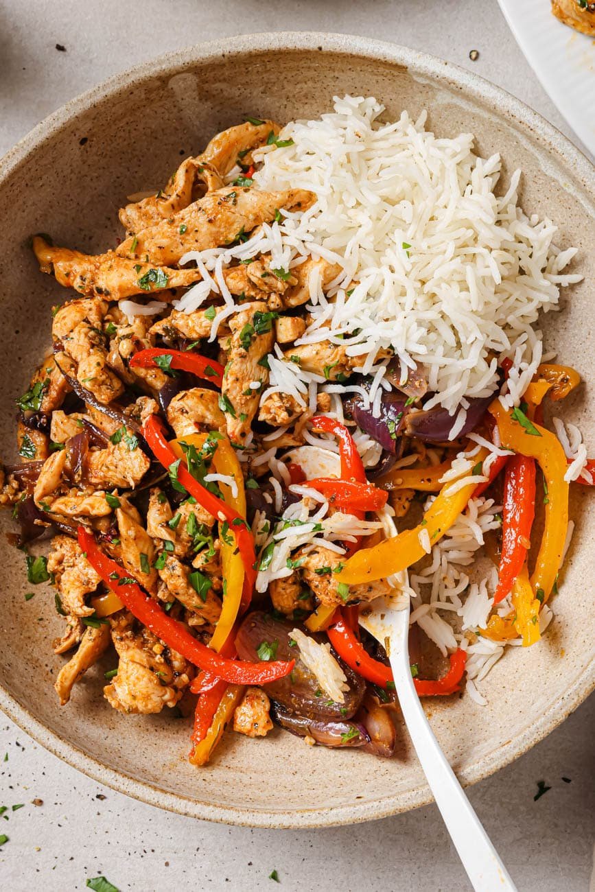 A bowl of chicken and peppers with white rice.