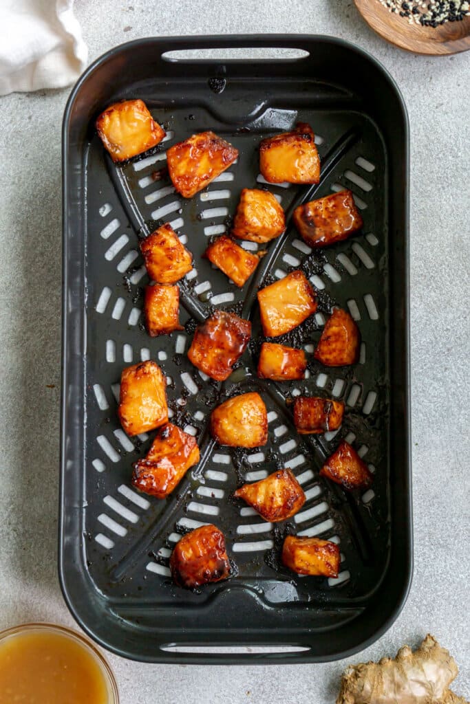 Cooked miso salmon bites with crispy edges in an air fryer basket.