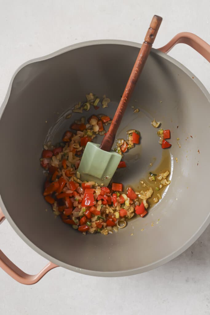 sautéeing vegetables in a pot with a spatula.