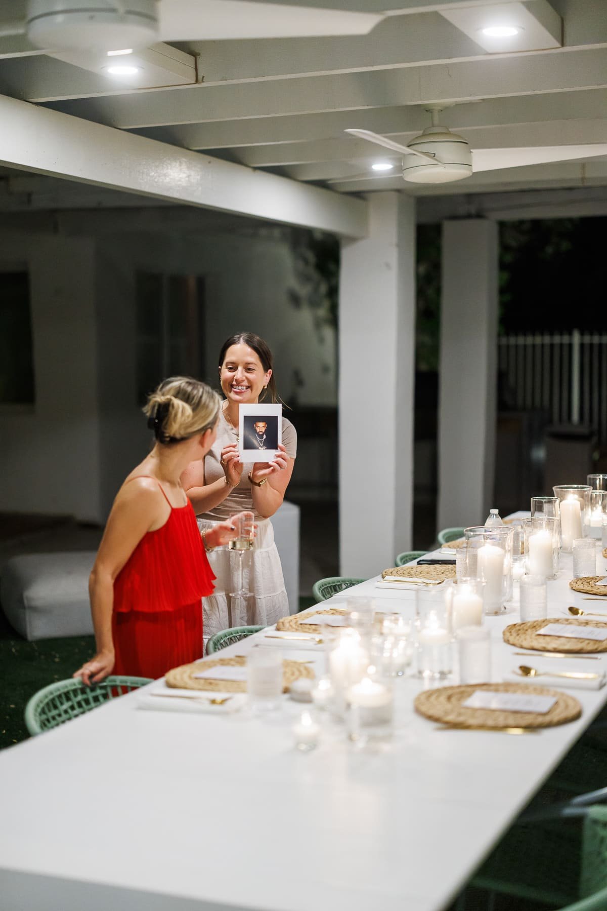 two girls at a dinner table, one wearing a red dress and the other in a white skirt.