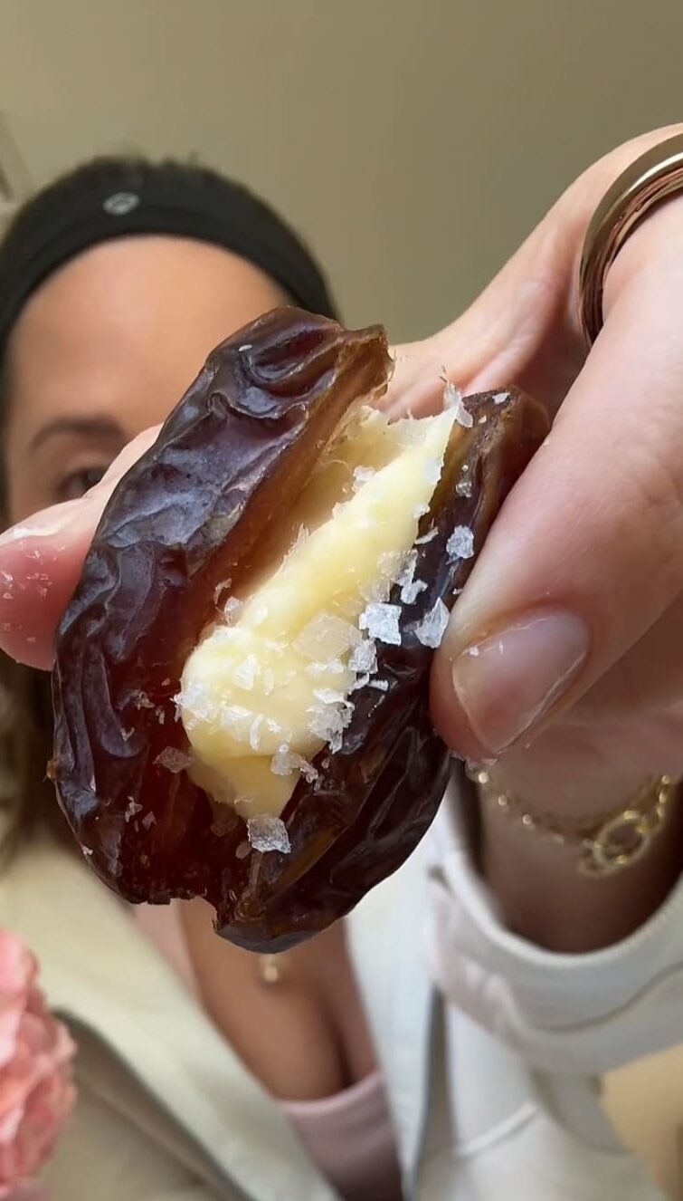 a hand holding a date stuffed with butter up to the camera.