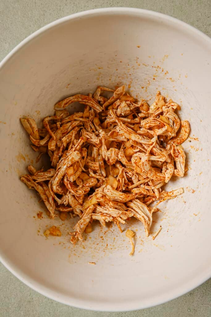 Seasoned and cooked turkey in a white mixing bowl.