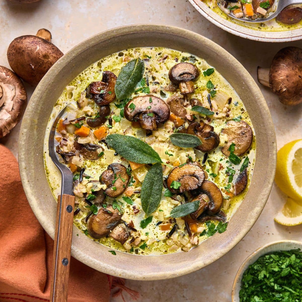 A bowl of mushroom and wild rice soup with ingredients on the table around it.