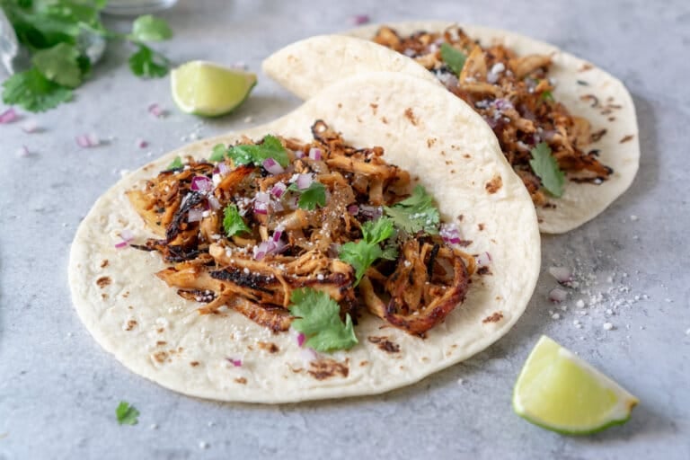 Turkey tacos garnished with cilantro and red onion with lime wedges.