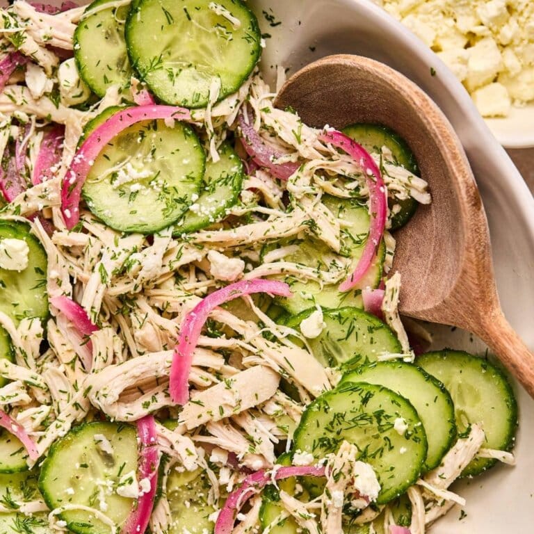 Chicken cucumber salad in a serving bowl with a wooden spoon.