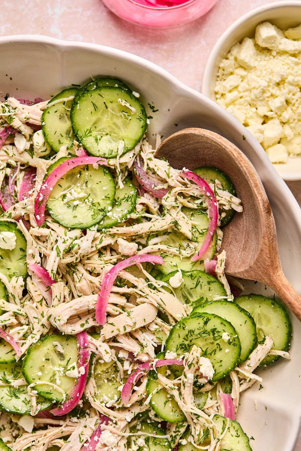 A serving bowl with chicken cucumber salad.