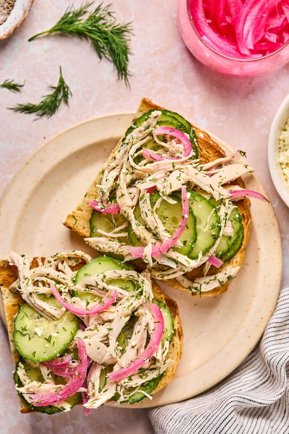 Two slices of toasted bread topped with chicken cucumber salad.