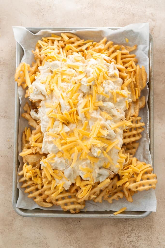 Adding crab and cream cheese mixture to waffle fries.