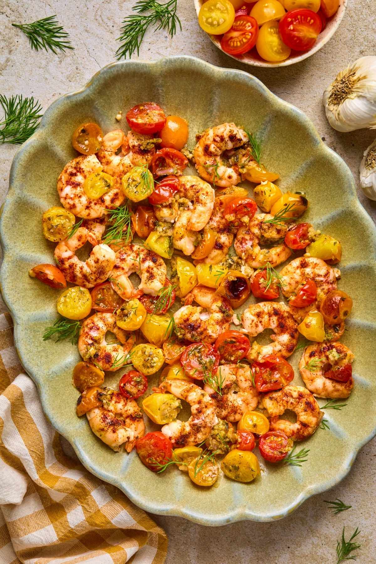 A green serving dish with sheet pan shrimp.