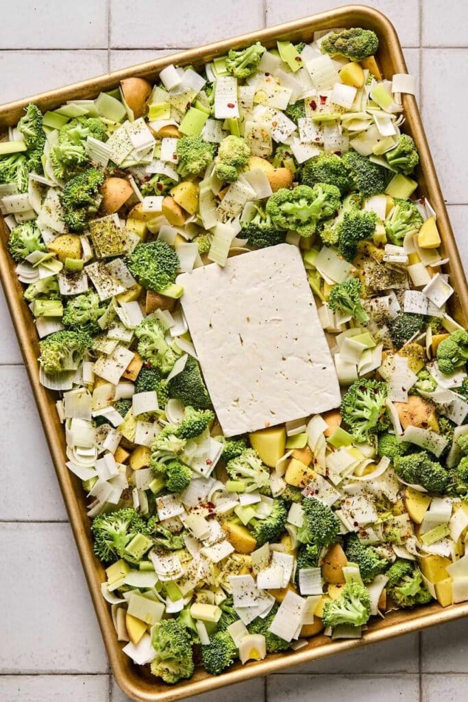 A baking sheet with feta, potatoes, broccoli, and leeks.