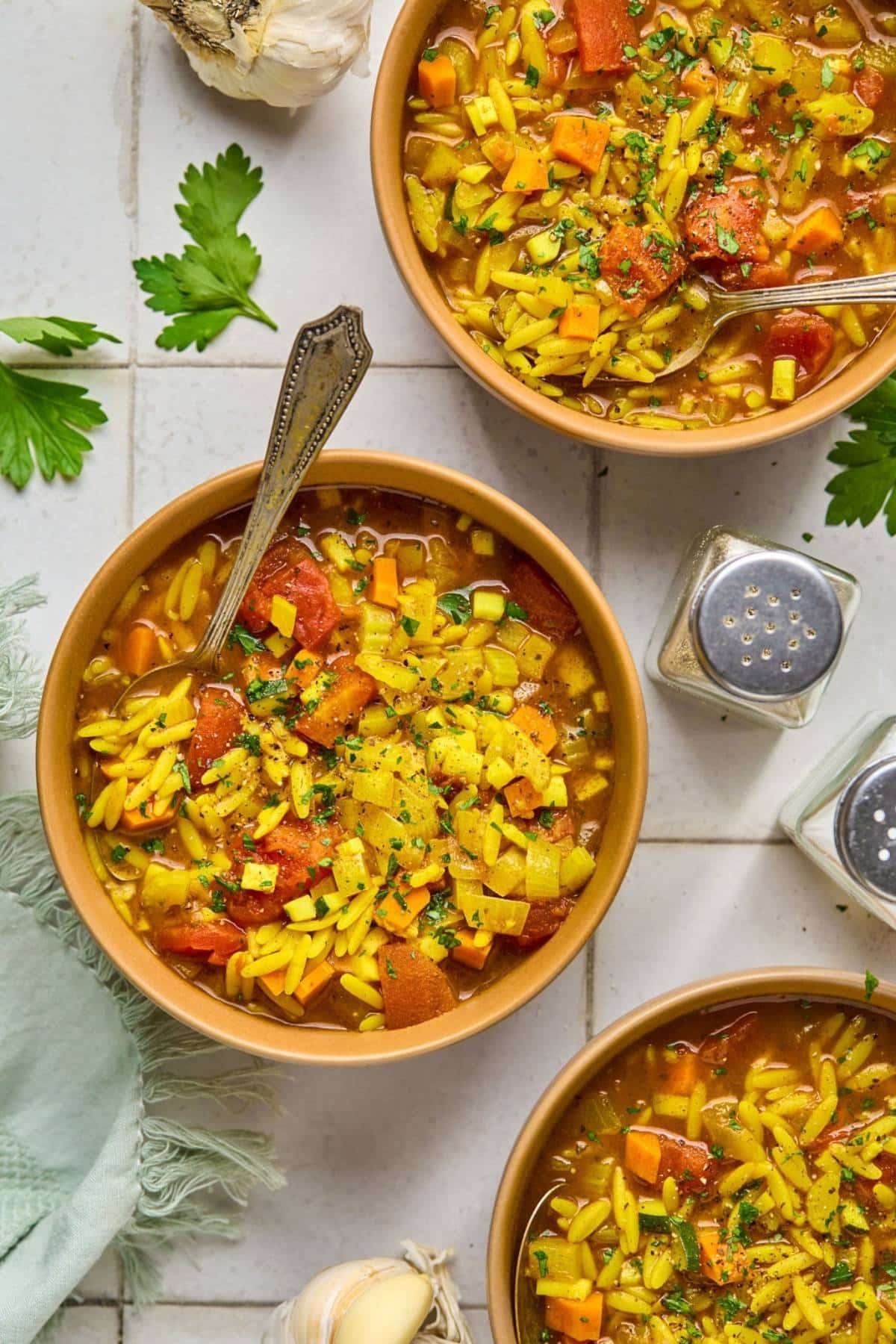 Several bowls of vegetable orzo soup.