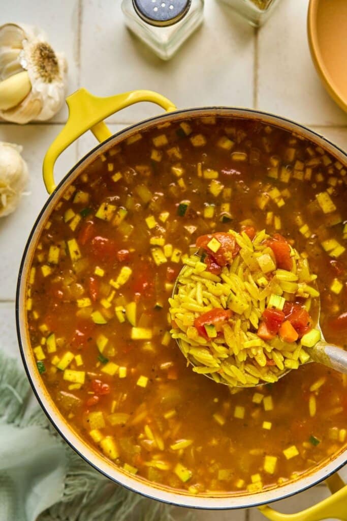 Adding orzo to a soup pot.