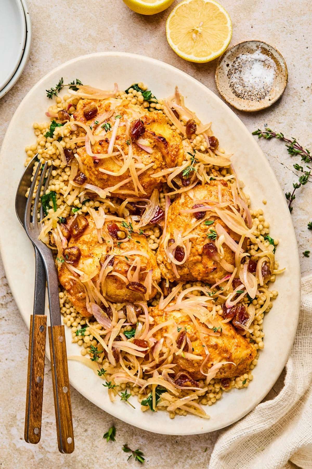 A plate of baked chicken thighs with couscous.