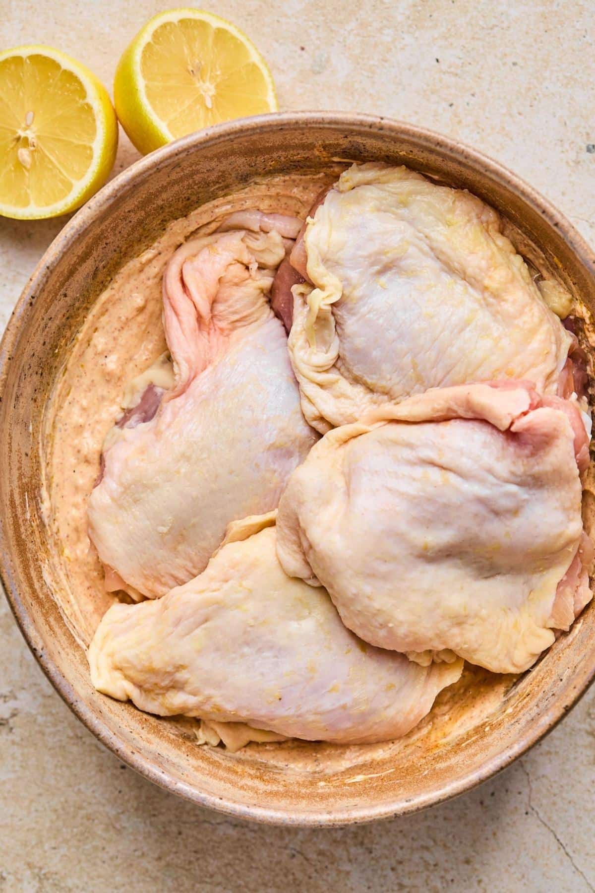 Chicken thighs in a bowl with marinade.