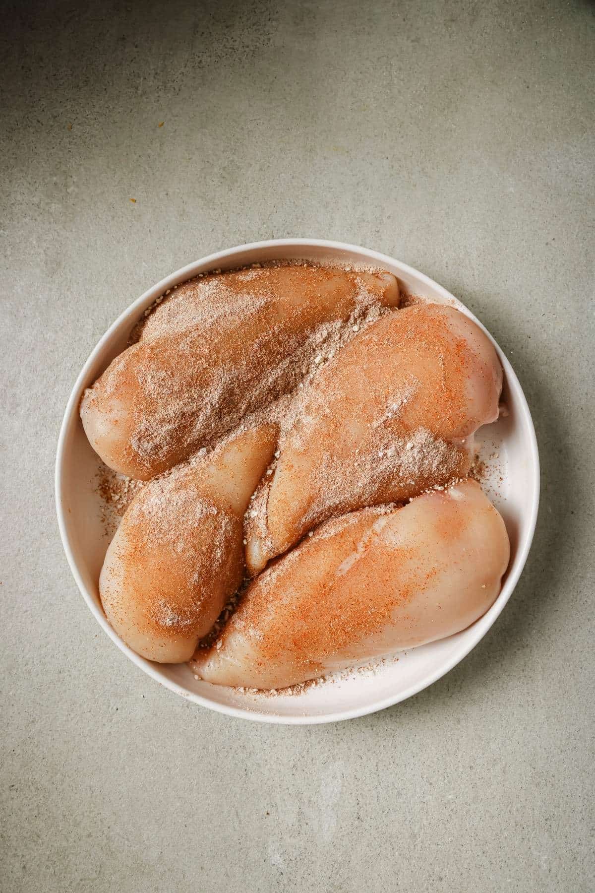 Seasoned chicken breasts on a white plate.