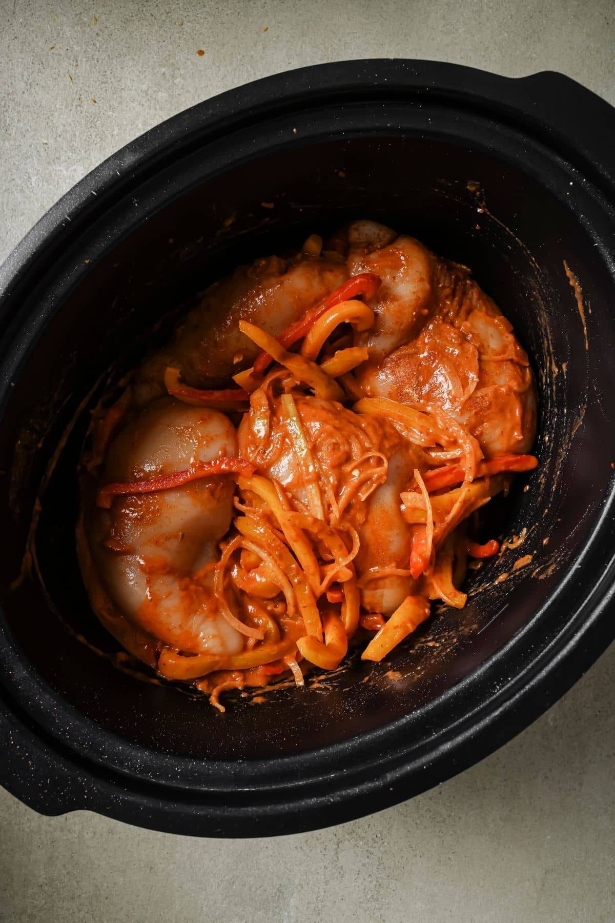 Enchilada sauce, yogurt, veggies, and chicken in a slow cooker.