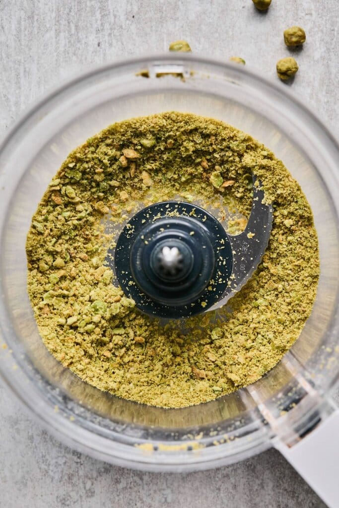 A food processor full of crushed wasabi peas.