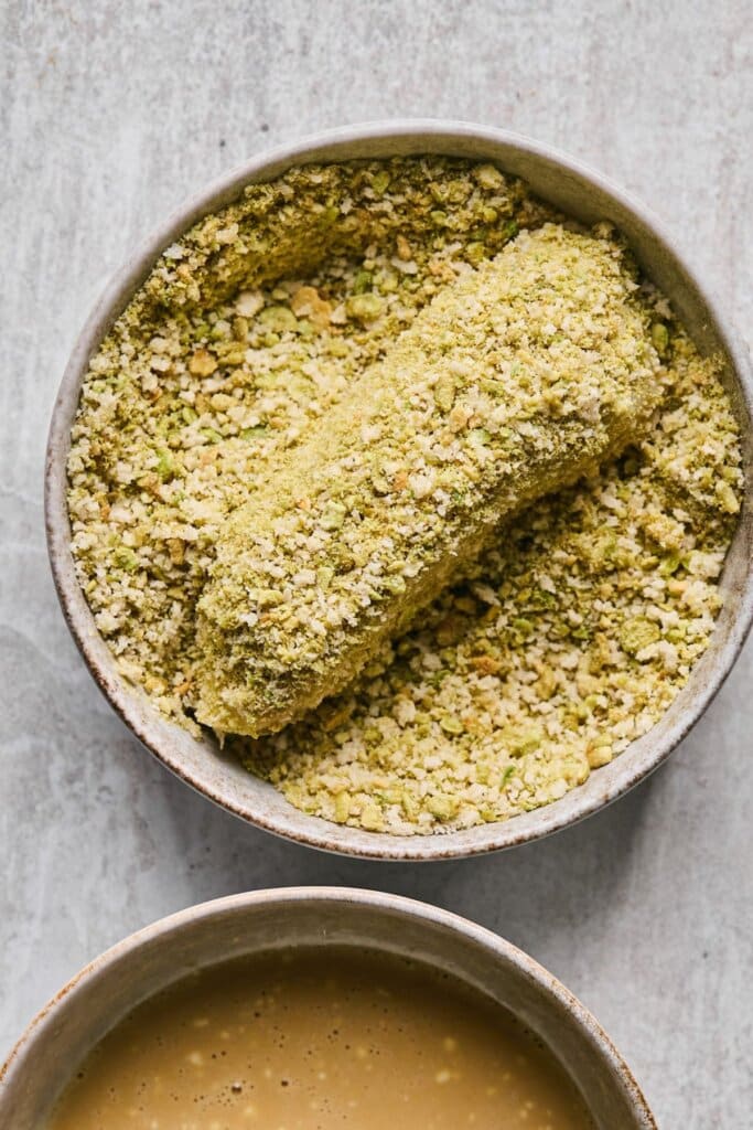 Covering a halibut filet with wasabi breadcrumbs.