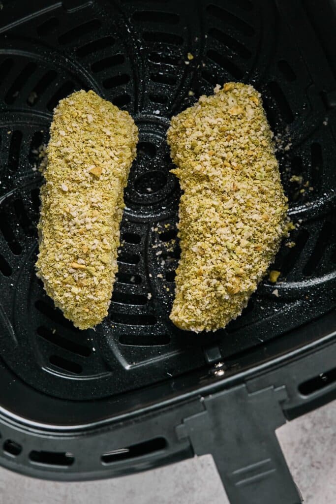 Breaded halibut filets in the air fryer basket.