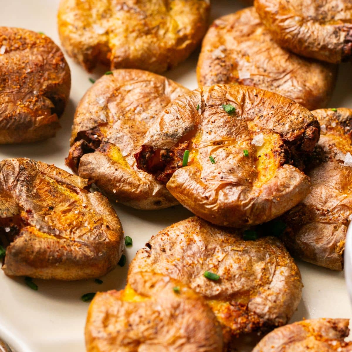 Air fryer smashed potatoes on a white serving platter.