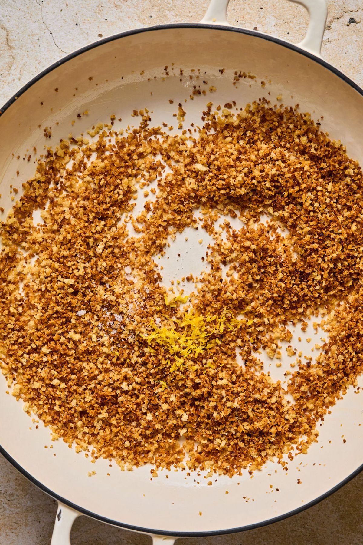 Toasted breadcrumbs in a skillet with lemon zest added.