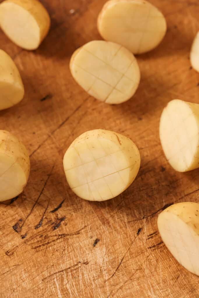 Scored baby potatoes on a cutting board.