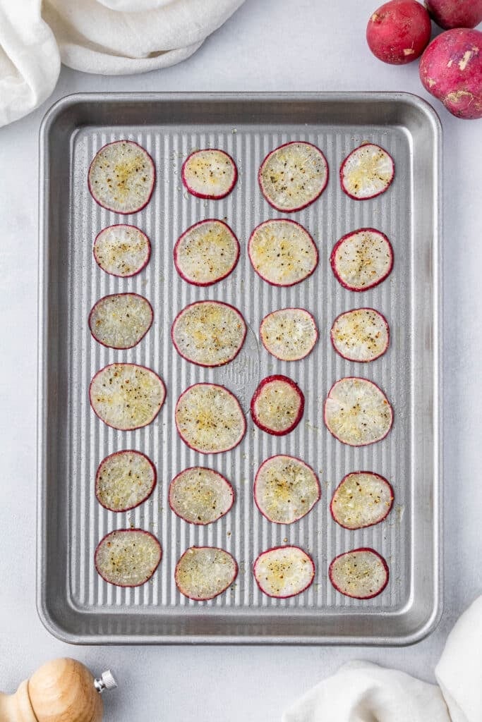 Seasoned radish slices on a sheet pan.