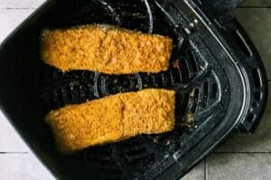 Golden brown halibut filets in the air fryer basket.