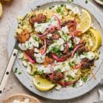 A plate of air fryer greek chicken skewers with lemon wedges and rice.