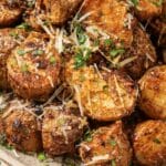 Halved potatoes in a bowl with parsley and parmesan cheese on top.