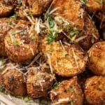 Halved potatoes in a bowl with parsley and parmesan cheese on top.