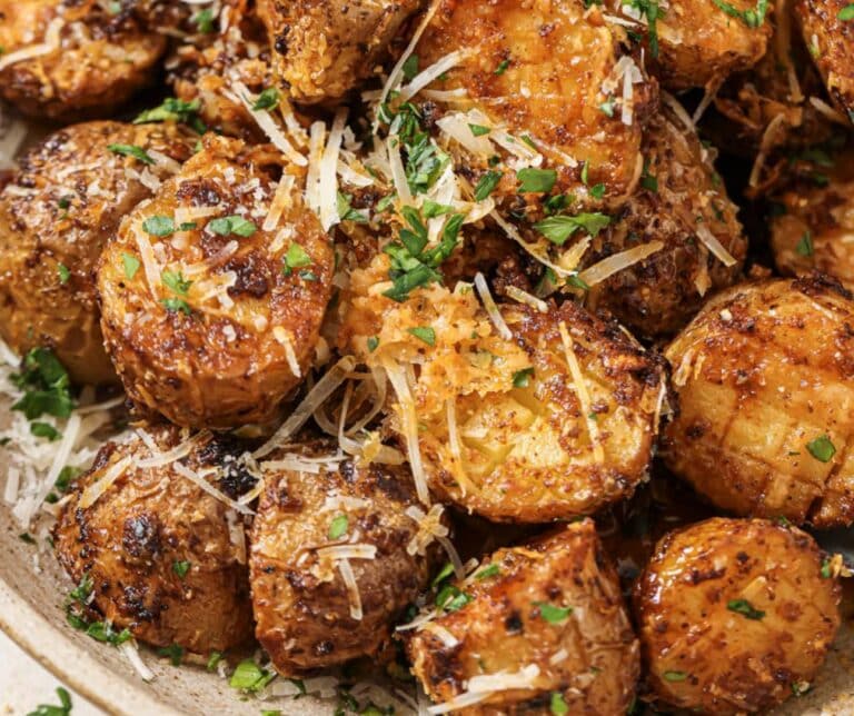 Halved potatoes in a bowl with parsley and parmesan cheese on top.