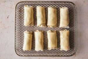 Egg rolls in an air fryer basket.